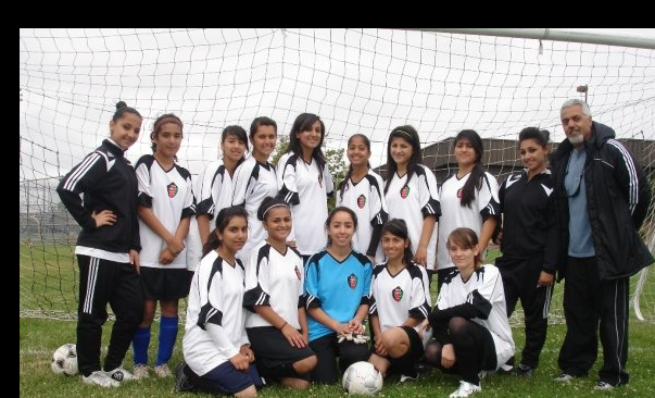 Atta Arghandiwal with the young women's soccer team he coached in Tracy.